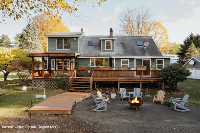 rear view of house with a yard, a fire pit, and a wooden deck