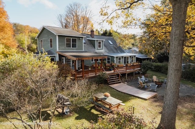 back of property featuring a fire pit, a lawn, and a wooden deck