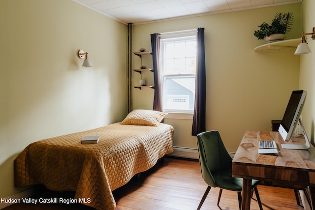 bedroom with light wood-type flooring, ornamental molding, a baseboard radiator, and multiple windows