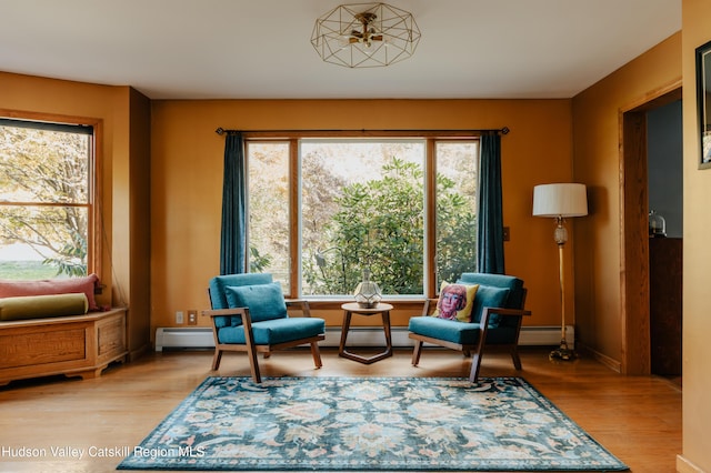 living area featuring light wood-type flooring, a wealth of natural light, and a baseboard heating unit