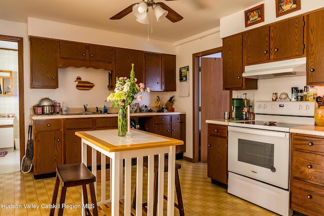 kitchen with white electric range oven, light floors, ceiling fan, under cabinet range hood, and tile countertops