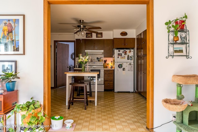 kitchen featuring freestanding refrigerator, light floors, under cabinet range hood, ceiling fan, and electric stove