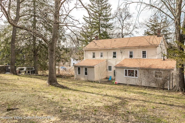 rear view of property featuring a yard and a chimney