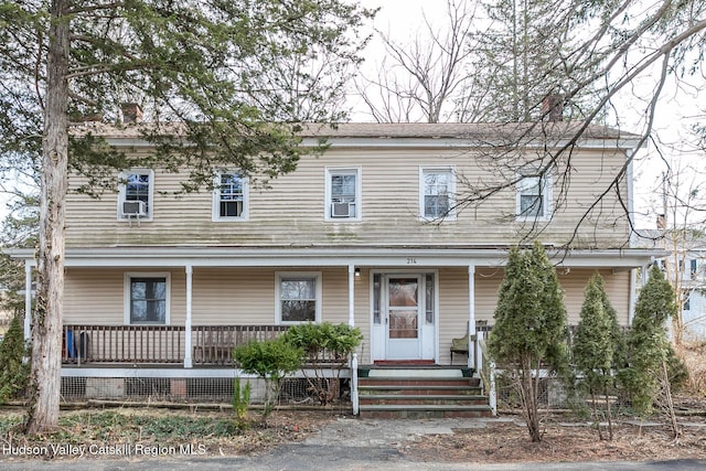 view of front of home with covered porch, a chimney, and cooling unit