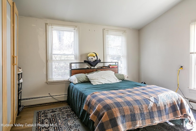 bedroom with a baseboard radiator and wood finished floors