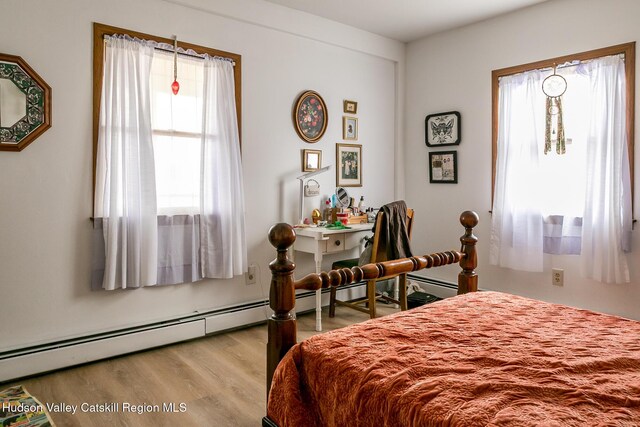 bedroom featuring wood finished floors and a baseboard heating unit