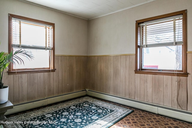 unfurnished room featuring wooden walls, wainscoting, and ornamental molding