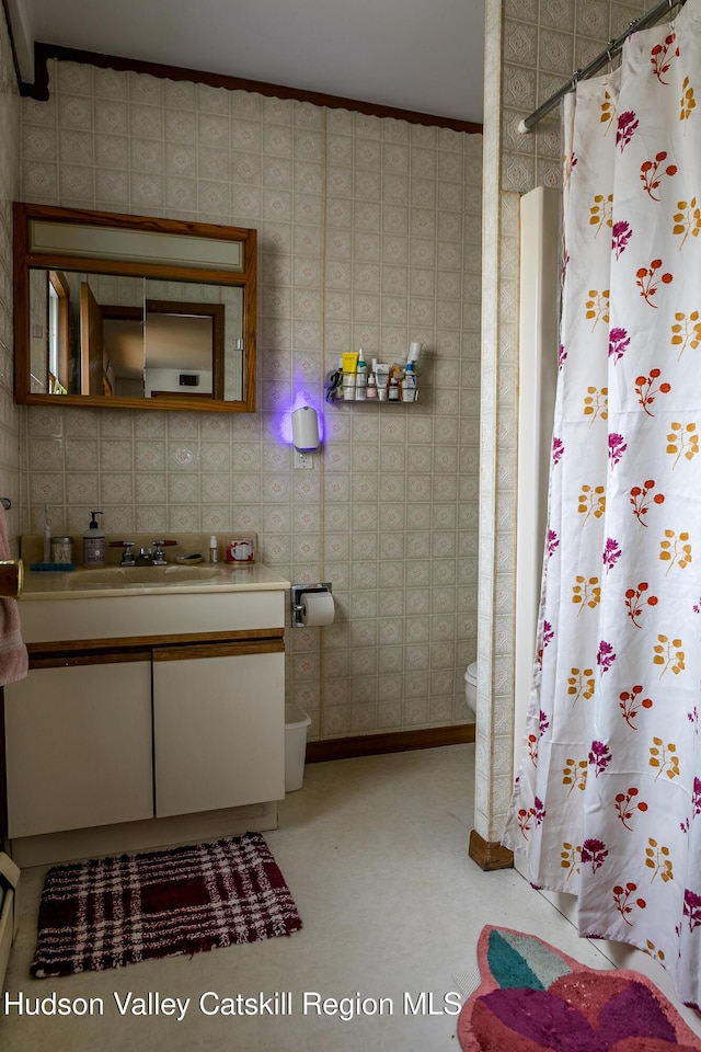bathroom featuring a shower with curtain, wallpapered walls, toilet, baseboards, and vanity
