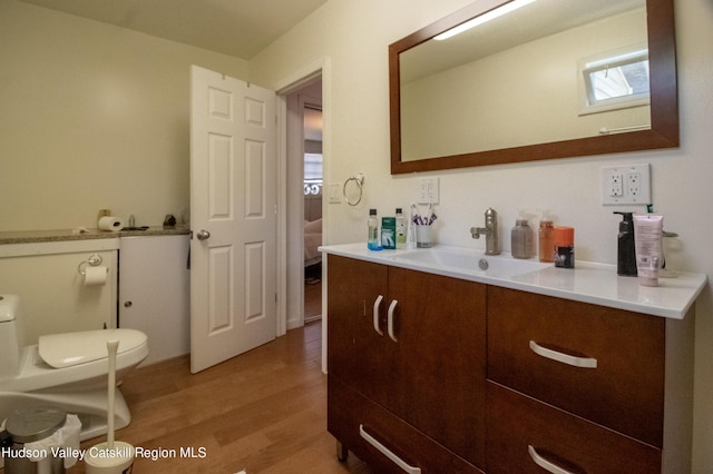 bathroom with toilet, vanity, and hardwood / wood-style flooring