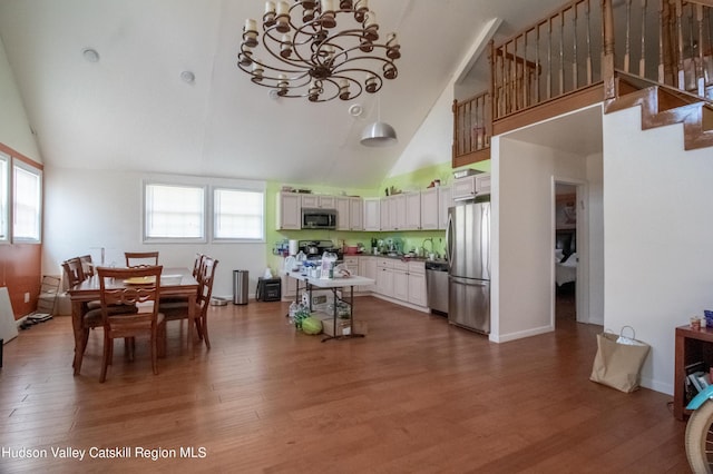 kitchen with plenty of natural light, white cabinetry, stainless steel appliances, and high vaulted ceiling