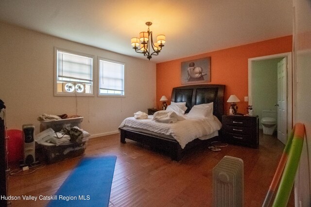 bedroom featuring hardwood / wood-style flooring, ensuite bath, and a notable chandelier