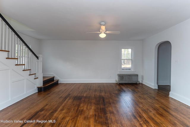 unfurnished living room with ceiling fan, dark hardwood / wood-style flooring, and radiator