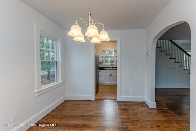 unfurnished dining area with a notable chandelier, plenty of natural light, dark hardwood / wood-style flooring, and sink