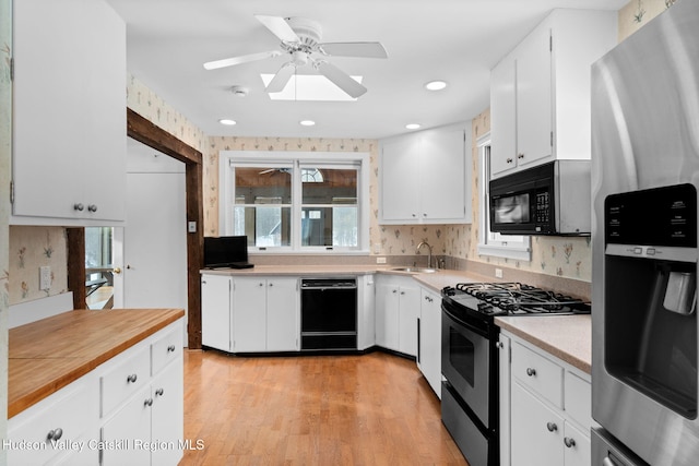 kitchen with white cabinetry, sink, light hardwood / wood-style floors, and black appliances