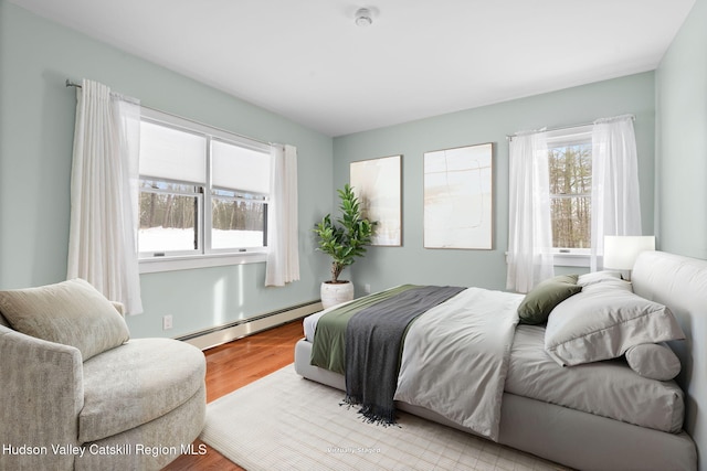 bedroom with light hardwood / wood-style flooring and baseboard heating