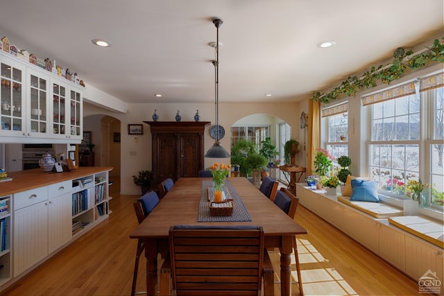  - dining space featuring arched walkways, light wood-style floors, and recessed lighting