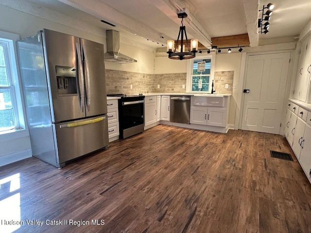 kitchen with hanging light fixtures, wall chimney exhaust hood, tasteful backsplash, white cabinetry, and stainless steel appliances