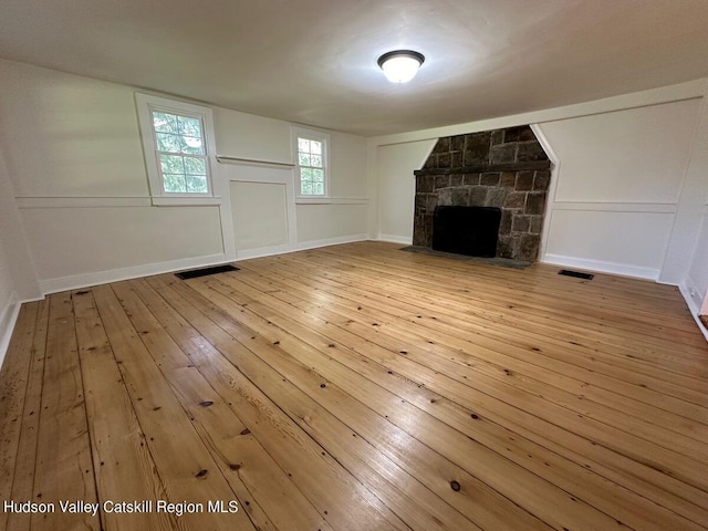 unfurnished living room with a stone fireplace and light hardwood / wood-style flooring