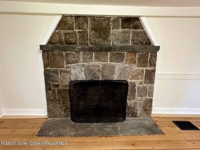 room details with a stone fireplace and hardwood / wood-style floors