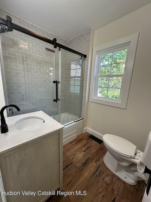 full bathroom featuring hardwood / wood-style floors, vanity, toilet, and enclosed tub / shower combo