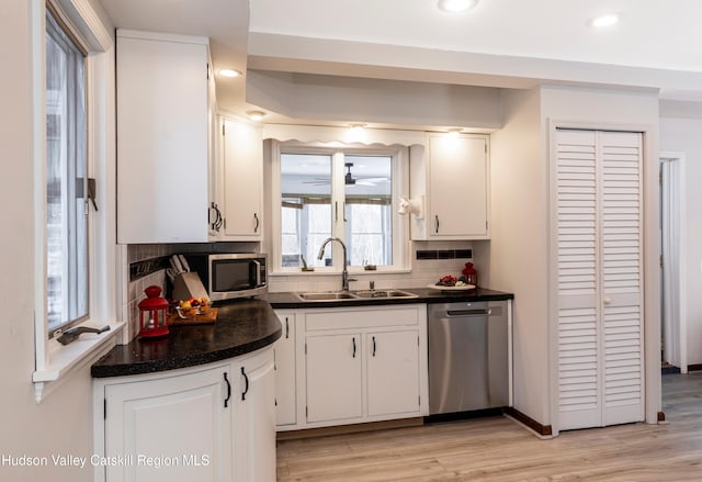 kitchen featuring sink, appliances with stainless steel finishes, backsplash, light hardwood / wood-style floors, and white cabinets