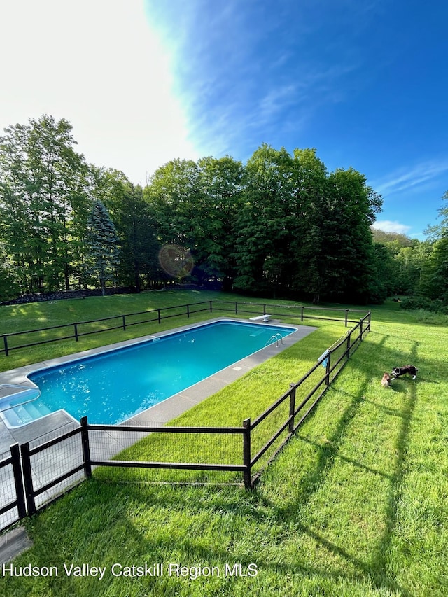 view of pool with a lawn and a diving board