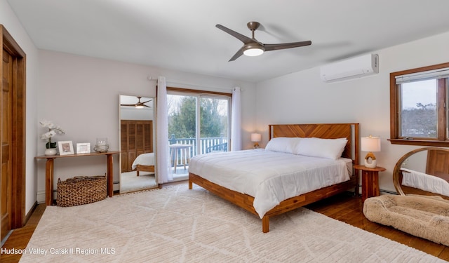 bedroom featuring a wall mounted air conditioner, light hardwood / wood-style flooring, a baseboard radiator, ceiling fan, and access to exterior