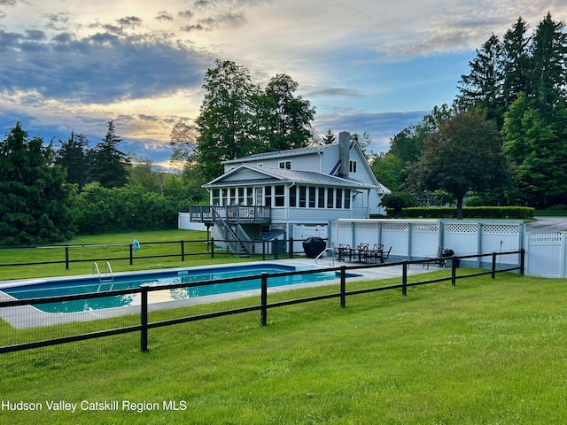 view of pool featuring a wooden deck, a patio, and a lawn