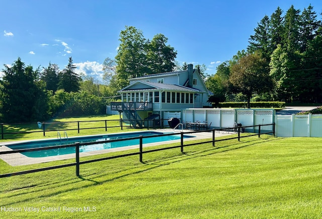 view of swimming pool featuring a sunroom and a yard