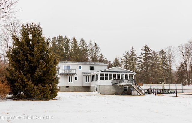 snow covered back of property with a sunroom