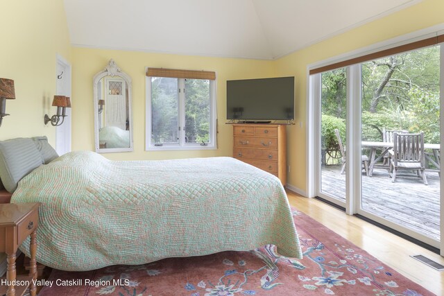 bedroom featuring vaulted ceiling, light wood-type flooring, multiple windows, and access to outside