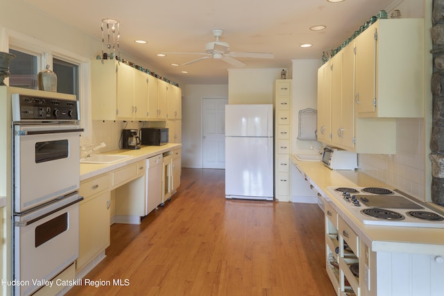 kitchen with sink, white appliances, light hardwood / wood-style flooring, ceiling fan, and decorative backsplash