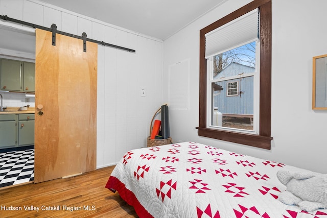 bedroom with hardwood / wood-style floors and a barn door