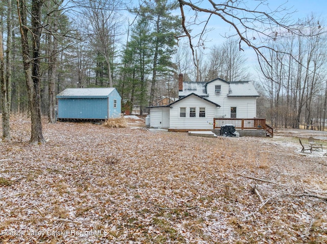 rear view of house with a deck and a storage unit