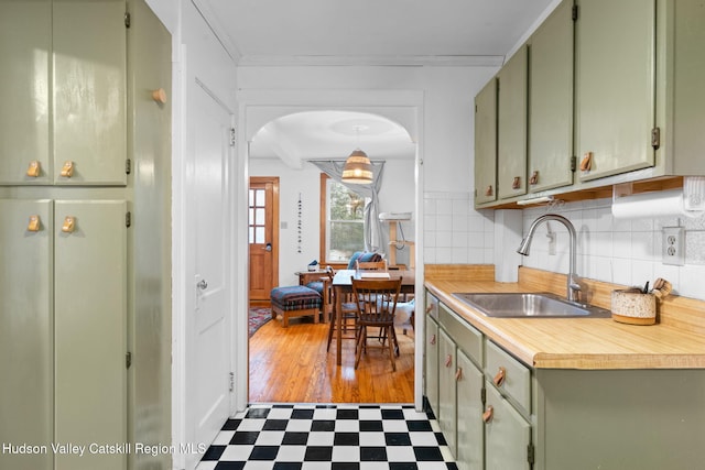 kitchen featuring tasteful backsplash, crown molding, sink, green cabinetry, and white fridge