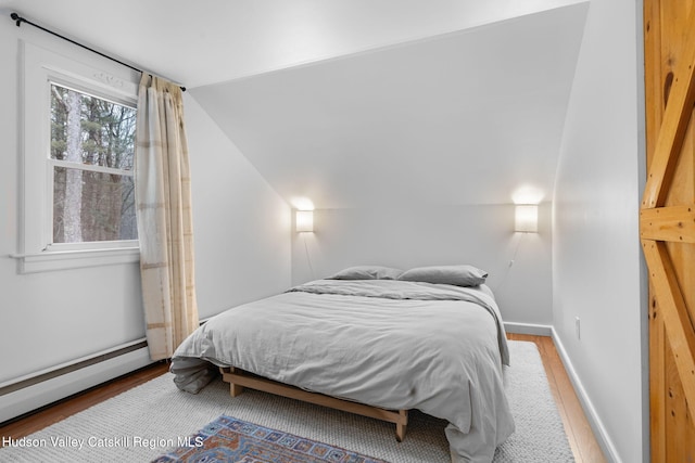 bedroom with baseboard heating, wood-type flooring, and lofted ceiling