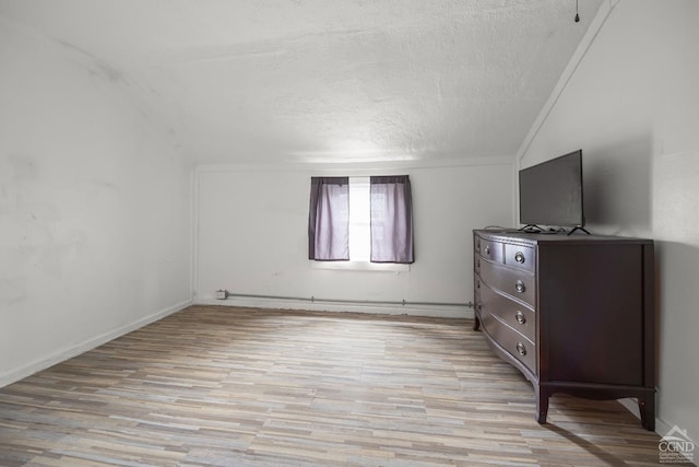 170 County Route 7a Unit 1, Copake, NY 12516 - unfurnished bedroom with a textured ceiling, vaulted ceiling, and light wood-style flooring