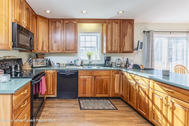 kitchen with black appliances, recessed lighting, light wood-type flooring, and a sink