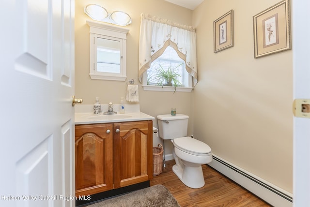 half bathroom with baseboards, toilet, baseboard heating, wood finished floors, and vanity