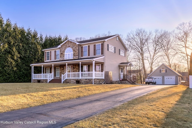 view of front of property featuring a front lawn, covered porch, an outdoor structure, a garage, and stone siding