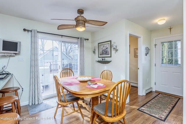 dining room with plenty of natural light, light wood-type flooring, and a baseboard heating unit