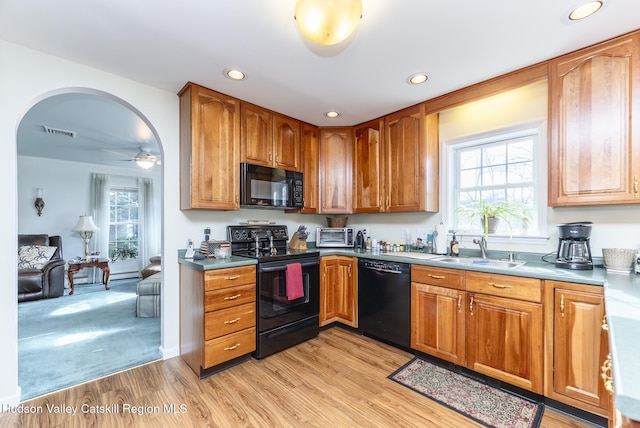 kitchen with a sink, visible vents, black appliances, and a healthy amount of sunlight