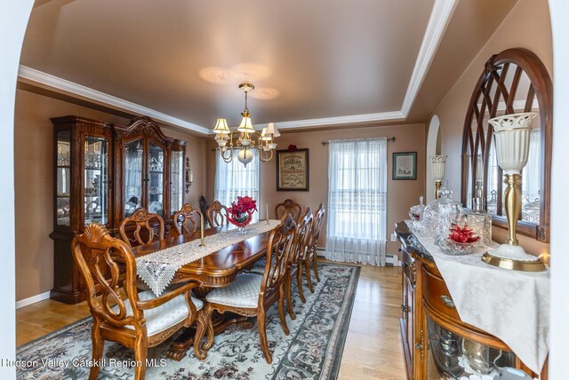 dining area featuring crown molding, baseboards, light wood finished floors, and a chandelier