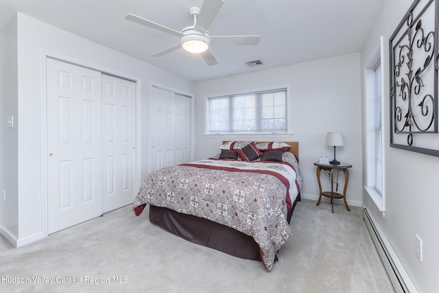 bedroom with a baseboard heating unit, multiple closets, carpet, and ceiling fan