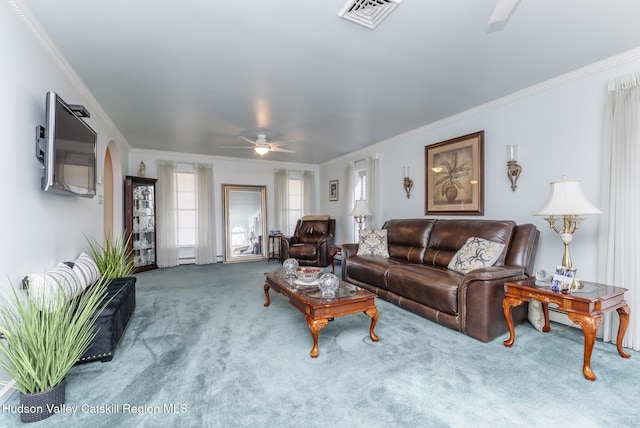 living area featuring visible vents, arched walkways, ceiling fan, crown molding, and carpet flooring