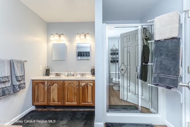 full bath featuring double vanity, a shower stall, baseboards, and a sink