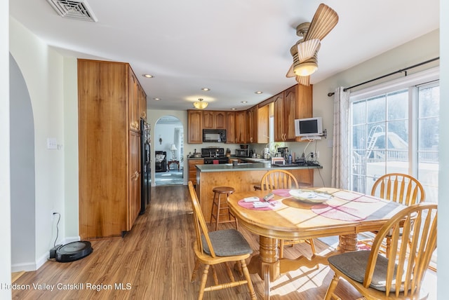 dining space featuring visible vents, wood finished floors, recessed lighting, arched walkways, and baseboards