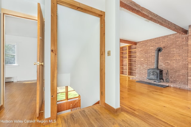 interior space with a baseboard heating unit, wood-type flooring, a wood stove, and beamed ceiling