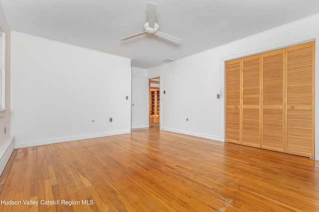 unfurnished bedroom featuring light wood-type flooring, a closet, baseboards, and ornamental molding