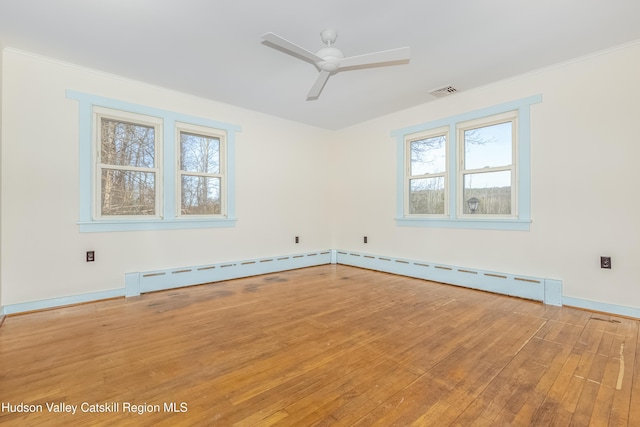 spare room with plenty of natural light, visible vents, hardwood / wood-style flooring, and ceiling fan